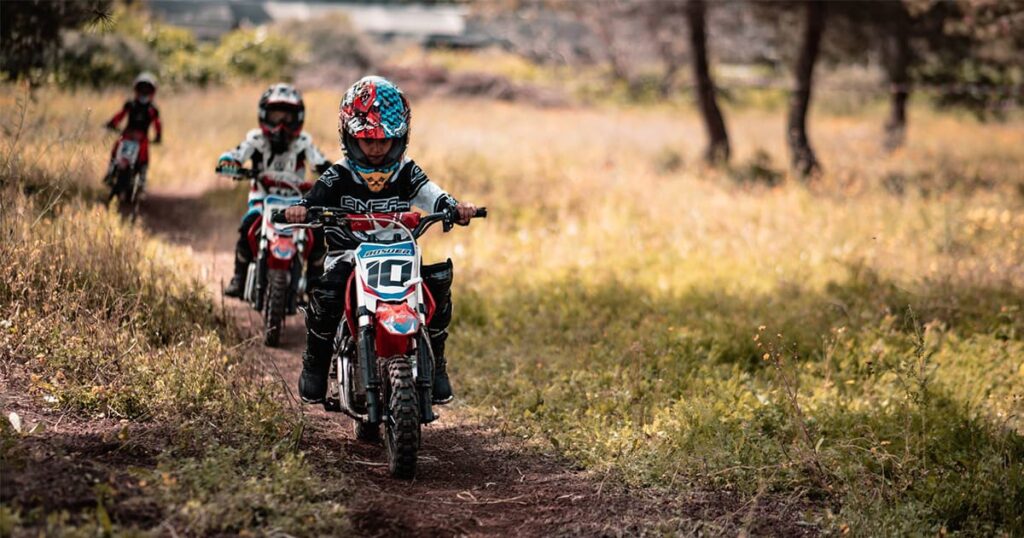3 kids driving dirt bike in a trail race