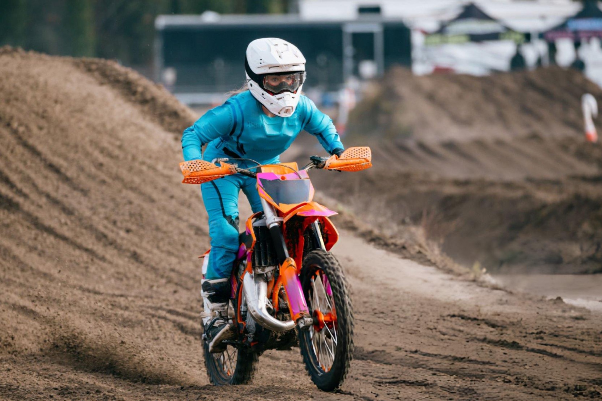 Imagen principal que muestra una motocicleta todoterreno de 50 cc en una pista de tierra con velocímetro superpuesto e íconos de equipo de seguridad.