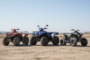ATV, 4-wheeler, and quad lined up side by side on rugged terrain, visually comparing their design and purpose differences.