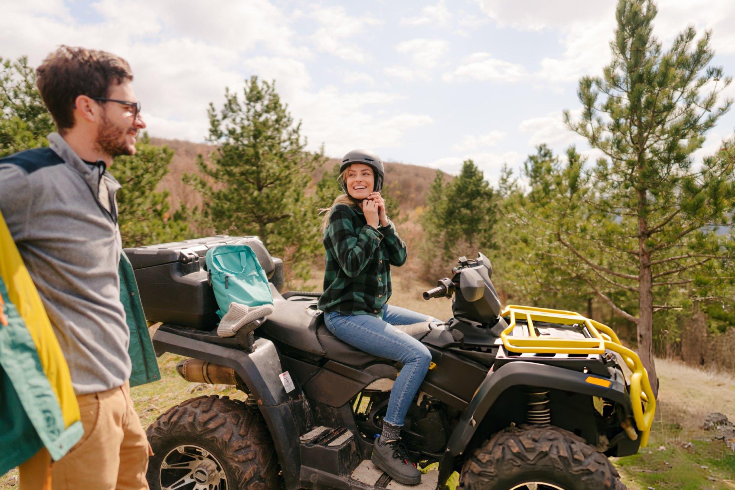 Beginner riding an ATV on a forest trail with full safety gear including a helmet, gloves, and boots, showcasing a safe and adventurous ride.