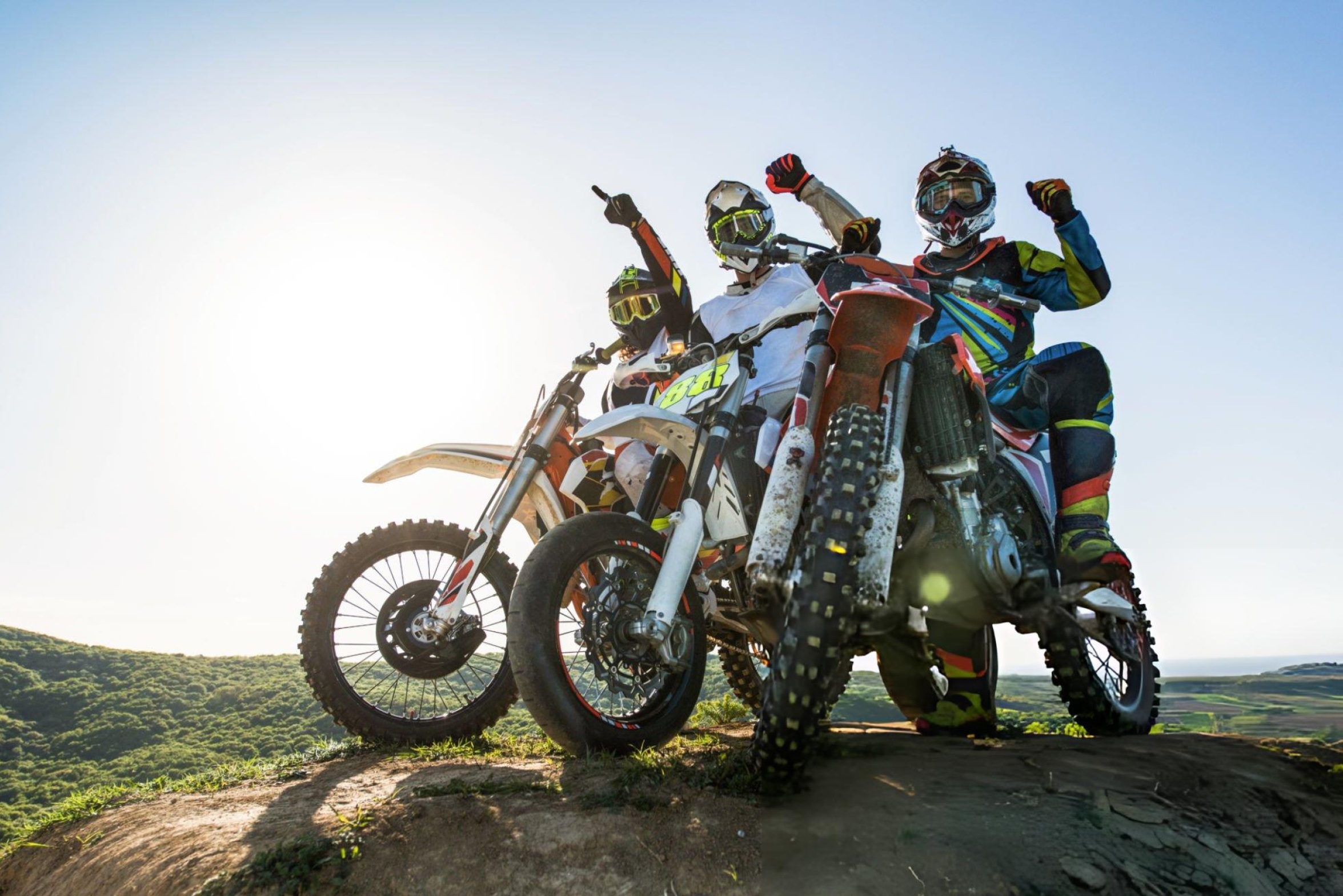 Professional motocross rider performing a jump on a dirt track with grandstands and flags in the background, highlighting the excitement of motocross racing.