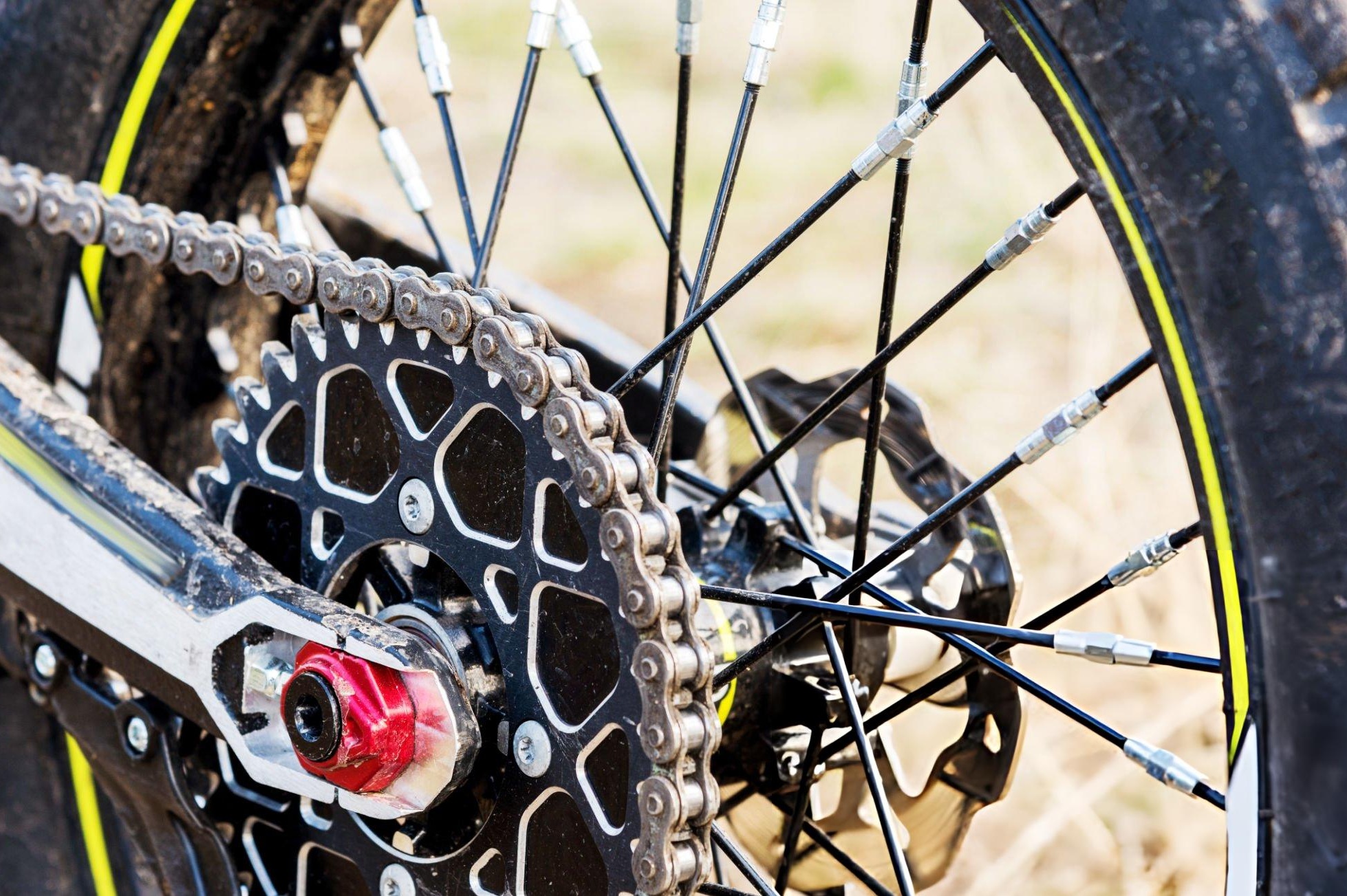 Checking dirt bike chain tension by measuring chain slack at the midpoint with a ruler