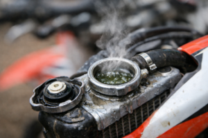 Boiling coolant at a dirt bike radiator cap showing a key overheating symptom that requires stopping immediately