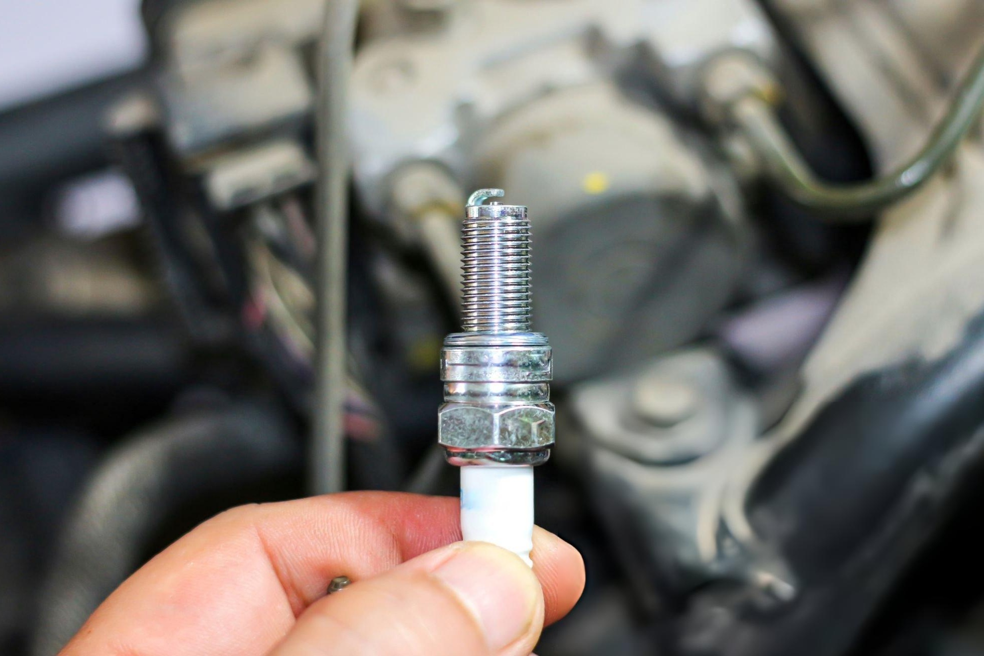 Mechanic checking a dirt bike spark plug to diagnose engine symptoms and performance issues